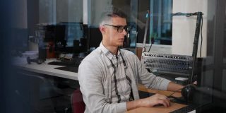 一个戴眼镜的年轻人在他办公室的电脑前工作