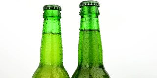 三个绿色啤酒瓶在白色啤酒瓶上旋转
