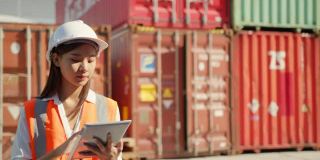 亚洲工程师领班女工人在集装箱货港进行检查，用压片装置装载货物集装箱。码头女工物流进出口船坞概念。