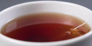 把红茶和茶包放在一个白色的杯子里搅拌