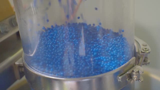 蓝色塑料颗粒在生产设备的移动。特写