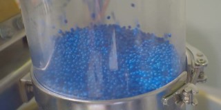 蓝色塑料颗粒在生产设备的移动。特写
