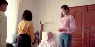 亚洲华人爷爷在家给孙子孙女发红包。快乐带着笑脸。