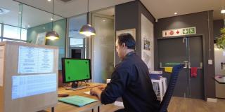 一个男性在开放式办公室使用科技进行交流的后视图