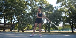8岁的美丽白人女孩穿着黑色芭蕾舞服在一个阳光明媚的夏天在城市公园跳芭蕾舞。慢动作200帧/秒