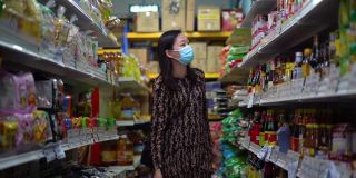 年轻的亚洲妇女戴着防护口罩在超市购物