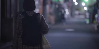 在冬天的晚上，年轻女子戴着防护面罩走在街上