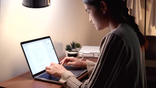 亚裔女性在家庭办公室工作。在电脑前工作。