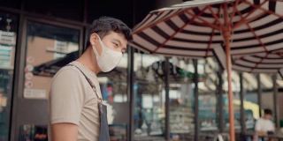 亚洲咖啡店的工作人员戴上外科口罩在店门口为顾客测温。