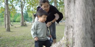 亚洲母亲和儿子在公园里看虫子