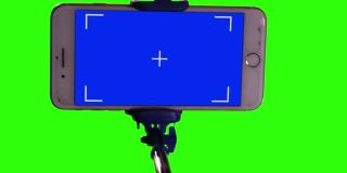 自拍杆蓝屏绿屏背景的智能手机。