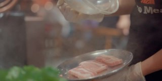 亚洲餐厅的员工戴着防护手套为顾客服务五花肉。
