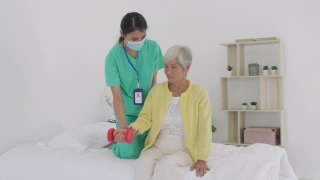 亚洲老年妇女在她的手腕关节炎接受关节炎物理治疗轻体重康复由专业护士或家庭健康助理在卧室在家。视频素材模板下载
