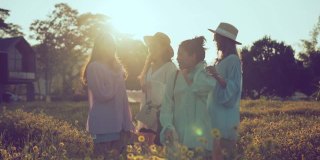 太阳耀光射线与亚洲女性朋友群笑笑快乐的一起旅行站在黄花花园农场自然的背景理念交谈