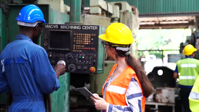 男技术员和女工头通过遥控器和片剂控制机器的操作。