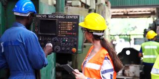 男技术员和女工头通过遥控器和片剂控制机器的操作。