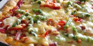 特写自制披萨配蔬菜，火腿和奶酪放在白色盘子里。最好的意大利美食。最喜欢的食物。隔离期间做饭。