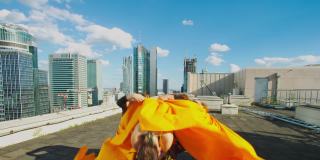 身穿迷彩服的女舞者在阳光明媚的屋顶上一起表演。橙色织物的现代编舞