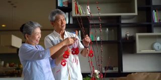 亚洲老夫妇在家里挂春节装饰品