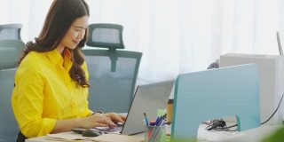 有吸引力的亚洲年轻女性工作与笔记本电脑微笑和写作的想法和要求成功的现代办公室或联合办公空间，创业概念
