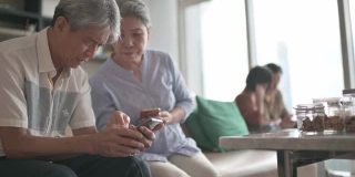 亚洲华人老年夫妇老花眼在周末闲暇时间试图在客厅学习使用智能手机有困难