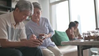 亚洲华人老年夫妇老花眼在周末闲暇时间试图在客厅学习使用智能手机有困难视频素材模板下载