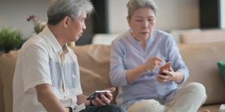 亚洲华人老年夫妇老花眼在周末闲暇时间试图在客厅学习使用智能手机有困难
