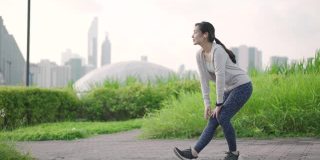 年轻的亚洲女子在城市户外跑步前做伸展运动