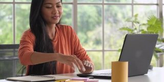 近距离亚洲妇女重新整理桌子上的东西和关闭笔记本电脑时，在家里完成工作