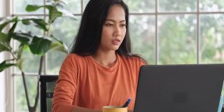 亚洲女性在家工作时，在笔记本电脑前做项目会感到压力。科技生活的新常态