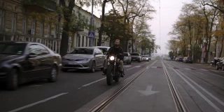 肌肉发达的男子与橙色易洛魁骑在城市的黄昏自行车
