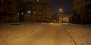 晚上，积雪覆盖的住宅楼前空荡荡的操场