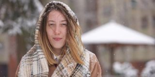 一名妇女抖掉头上的雪，戴上头巾，这样她就可以把落在脸上和头发上的雪清除掉