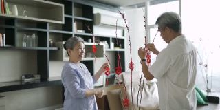 亚洲华人祖父母在庆祝春节期间装饰他们的家