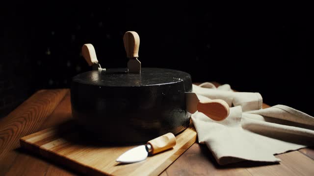 中等硬度的帕尔马干酪头放在木板上，配上帕尔马干酪刀。幻灯片拍摄