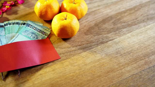 橘子和带有马来西亚货币的木制背景的中国红包