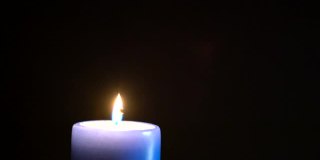 一支巨大的蓝色蜡烛在一片漆黑中燃烧。