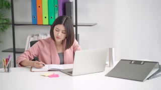 专注专注的亚洲女商人专业工作者写笔记规划思维创意创意策略，员工努力工作在现代办公室使用笔记本电脑技术视频素材模板下载