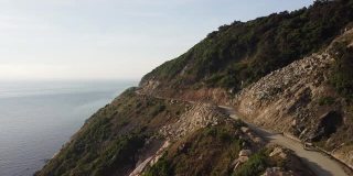 鸟瞰图的摩托车驾驶在危险的海岸悬崖边的道路。
