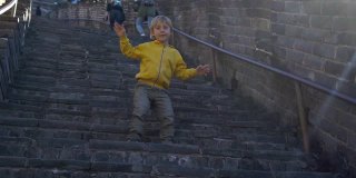一个快乐的小男孩在中国长城的楼梯上玩的慢镜头