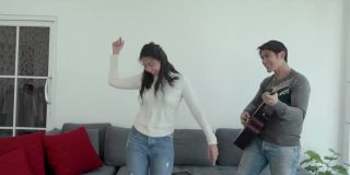 一对亚洲年轻夫妇一起弹吉他跳舞