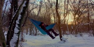 在冬天的森林里，人们躺在树下的吊床上