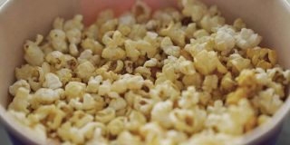 甜爆米花在桶里的特写。媒体。在电影院看电影的美味的甜爆米花。在电影院吃甜点。电影院的传统爆米花