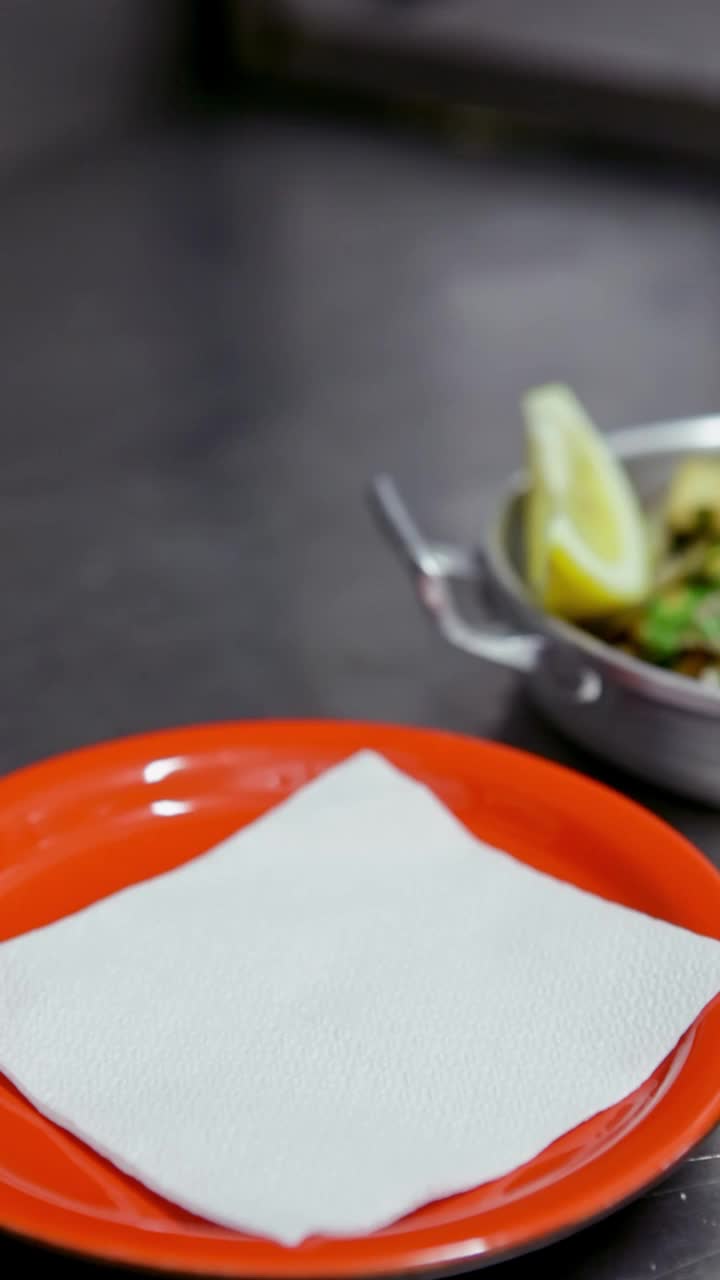 开胃的蛤蜊与大蒜，香草，摆在一个铝盘子，只有一个柠檬，厨师把一个红色的盘子。垂直视频。特写镜头。
