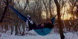 在冬天的森林里，人们躺在树下的吊床上