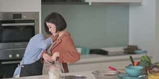 亚洲华人高级妇女帮助她的女儿穿上围裙准备做饭给家人
