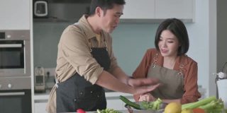 亚洲华人夫妇在厨房柜台准备食材为家人做饭