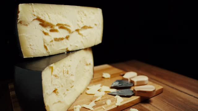 中等硬度的帕尔马干酪头放在木板上，配上帕尔马干酪刀。幻灯片拍摄