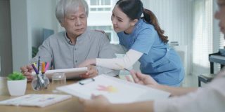 迷人的年轻老年亚洲公民夫妇坐在家里水彩画艺术品桌上与护士在心理健康治疗或亚洲老年人隔离活动生活方式感到快乐。