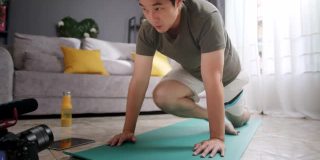 亚洲人健身教练教授或教练伸展下背部和手臂到他的在线学生在家锻炼。
